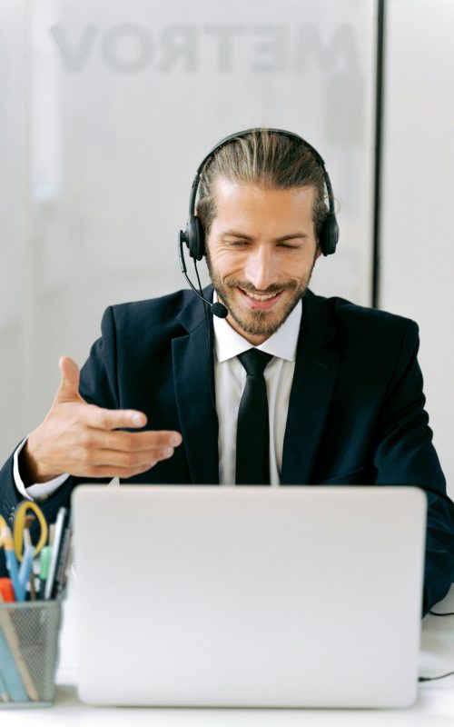 Confident businessman in suit with headset conducting an online meeting from office.