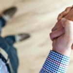 Close-up of a handshake between two people inside an office, symbolizing trust and cooperation.